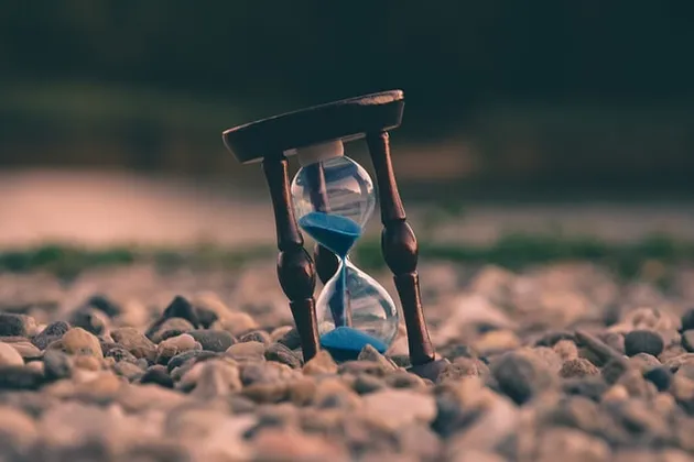 an hourglass on a stoney beach